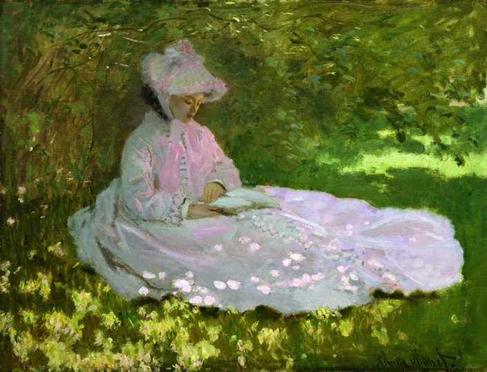 Jeune femme lisant assise dans l'herbe et les fleurs printanières
